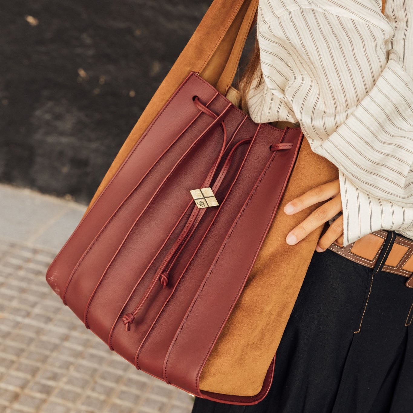 Bolso TABLAO Goya Borgoña. Bolso de mujer tipo saco bicolor, confeccionado en piel y ante en tonos burdeos y camel, con cierre de cordón ajustable y detalle metálico dorado.