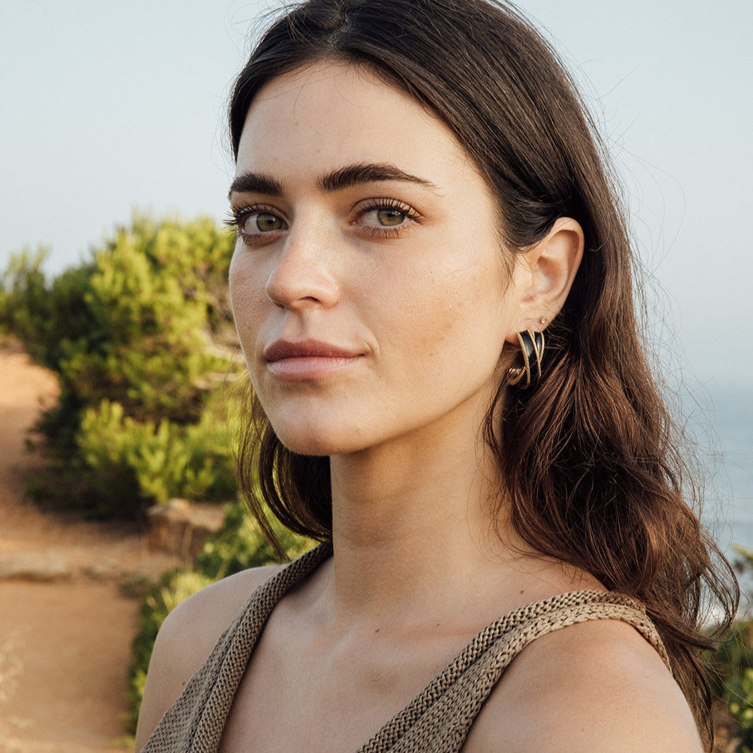 Pendientes LOLA negros en baño de oro, diseño en esmalte brillante y textura de cuerda trenzada. Made in Spain.